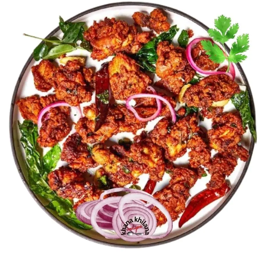 प्लेट में परोसी गई मसालेदार चिकन 65 रेसिपी, प्याज और करी पत्ते के साथ गार्निश किया हुआ